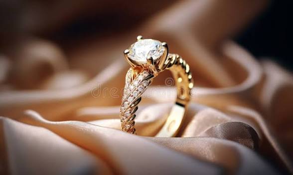 Anillo dorado con una piedra central brillante sobre tela satinada